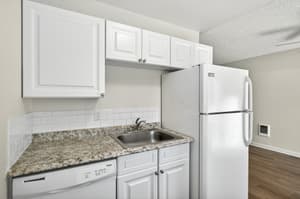 Apartment kitchen with granite countertops and white cabinets at Lincoln Court in Fairview, Oregon